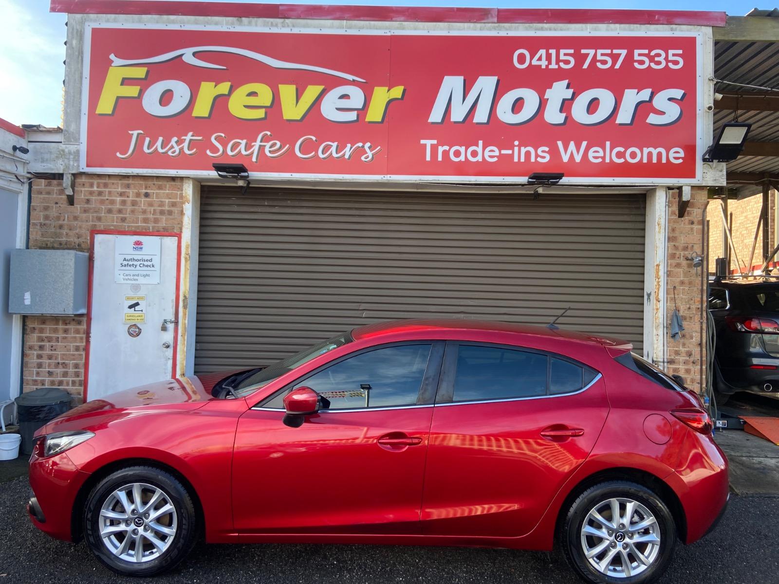 A red Mazda 3 parked side-on under the Forever Motors sign on The Entrance Road, Long Jetty